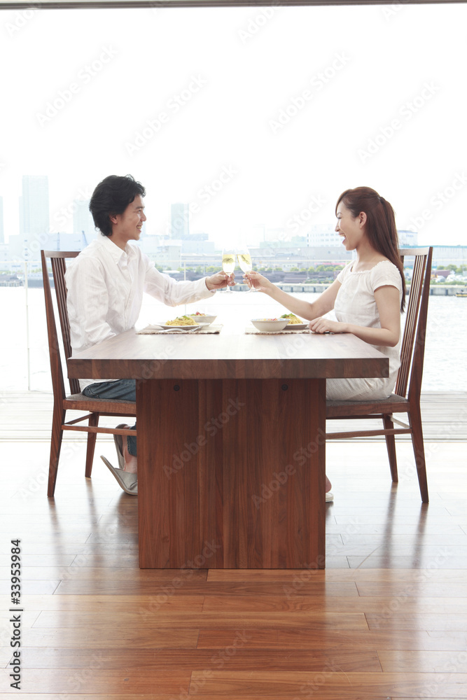 ダイニングテーブルで乾杯するカップル ダイニングテーブルで乾杯するカップル