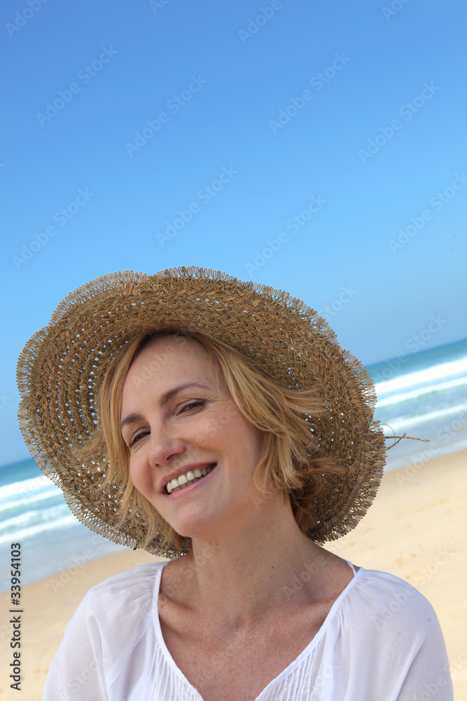 Smiling woman in a straw hat on the beach