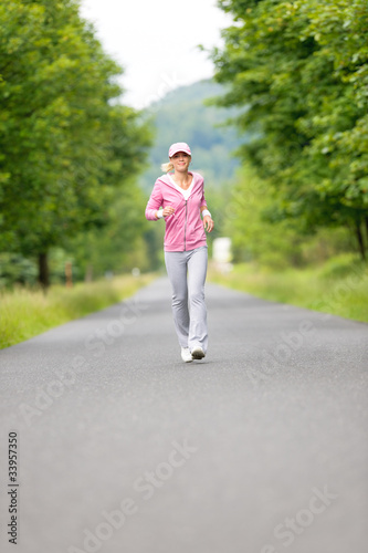 Jogging sportive young woman running park road