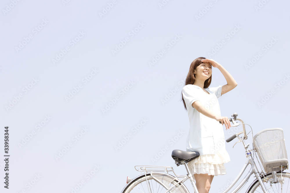 Naklejka premium 自転車を押しながら空を見上げる女性