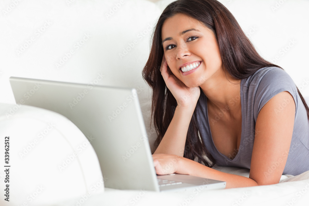 happy woman lying on sofa with notebook smiling into camera happy woman lying on sofa with notebook smiling into camera