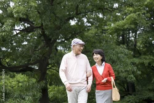 腕を組みながら公園を散歩する老夫婦 © paylessimages