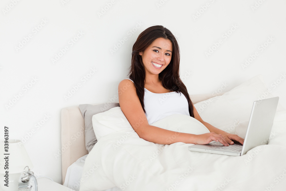 charming woman with notebook lying in bed looking into camera charming woman with notebook lying in bed looking into camera