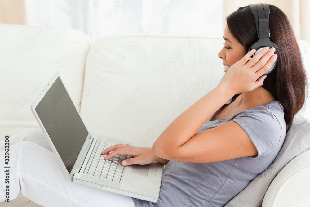 charming woman sitting on sofa with earphons on charming woman sitting on sofa with earphons on