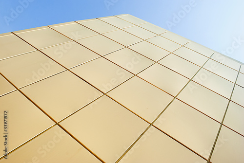 Facade wall of golden squares against the sky.