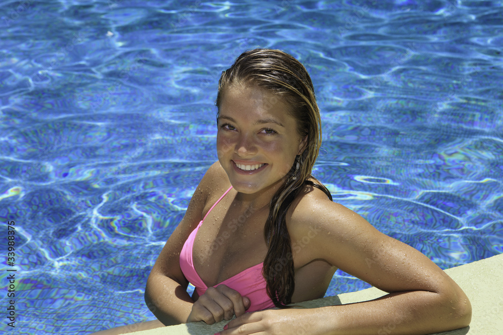 portrait of a teenage girl in pink bikini in a swimming pool