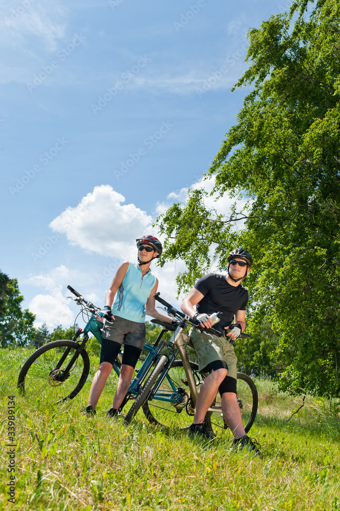 Sport mountain biking couple relax in meadows Sport mountain biking couple relax in meadows