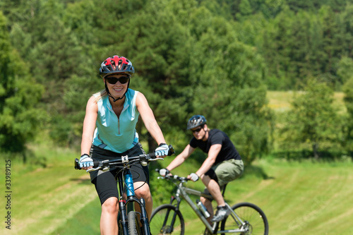 Fototapeta Naklejka Na Ścianę i Meble -  Sport mountain couple biking uphill sunny meadows