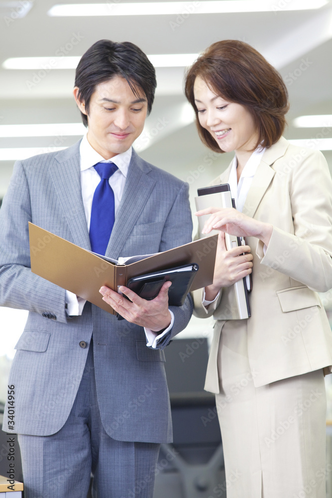 オフィスで会話をしているOLとビジネスマン オフィスで会話をしているOLとビジネスマン