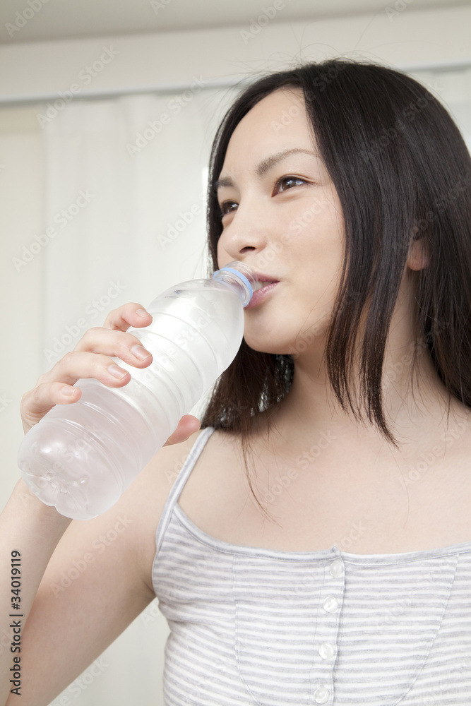 ペットボトルの水を飲む女性