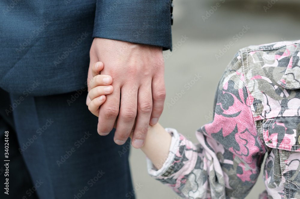 Closeup of a small girl holding an man's hand