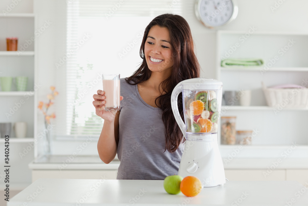 Attractive woman using a blender while holding a drink Attractive woman using a blender while holding a drink