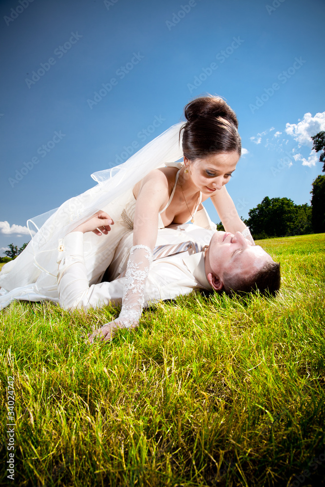 Young newly married couple lying on green lawn Young newly married couple lying on green lawn