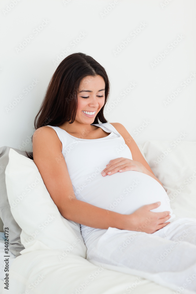 Frontal view of a good looking pregnant woman touching her belly Frontal view of a good looking pregnant woman touching her belly
