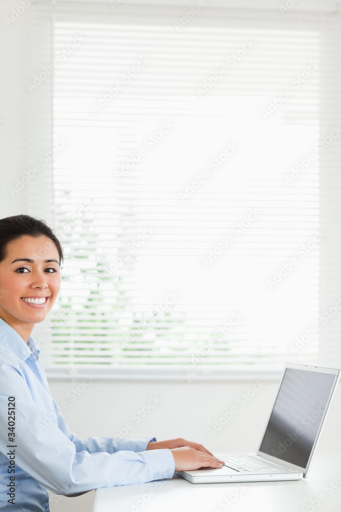 Beautiful woman working with her laptop and posing while sitting Beautiful woman working with her laptop and posing while sitting