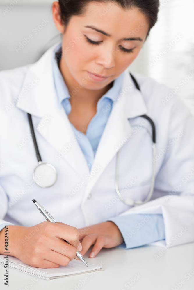 Beautiful female doctor writing on a scratchpad Beautiful female doctor writing on a scratchpad