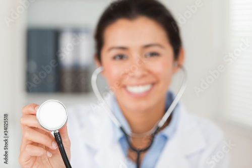 Attractive female doctor using a stethoscope while looking at th