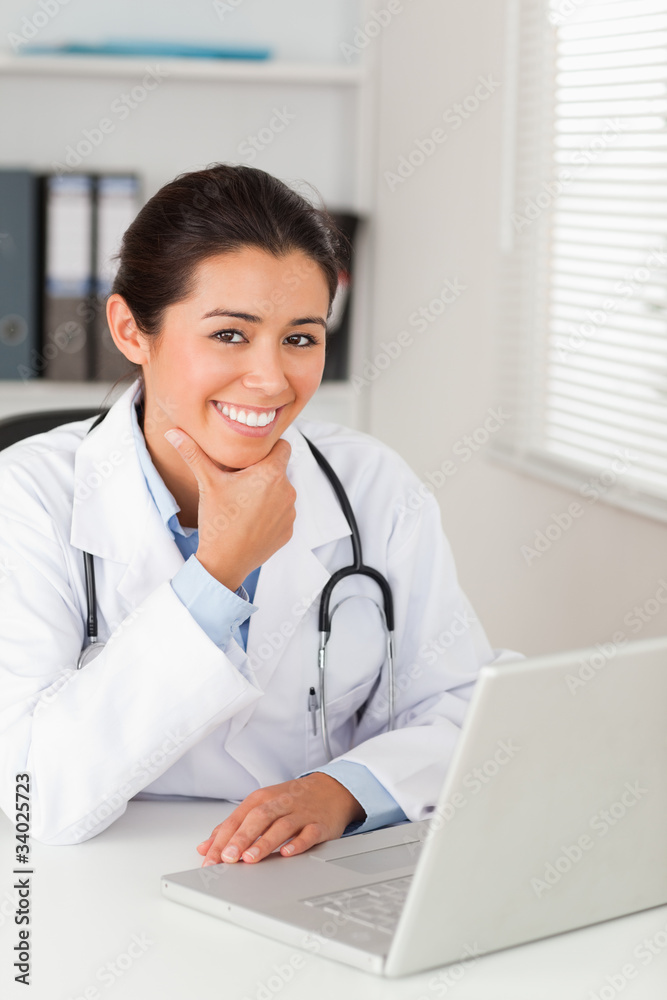 Beautiful female doctor working with her laptop while posing