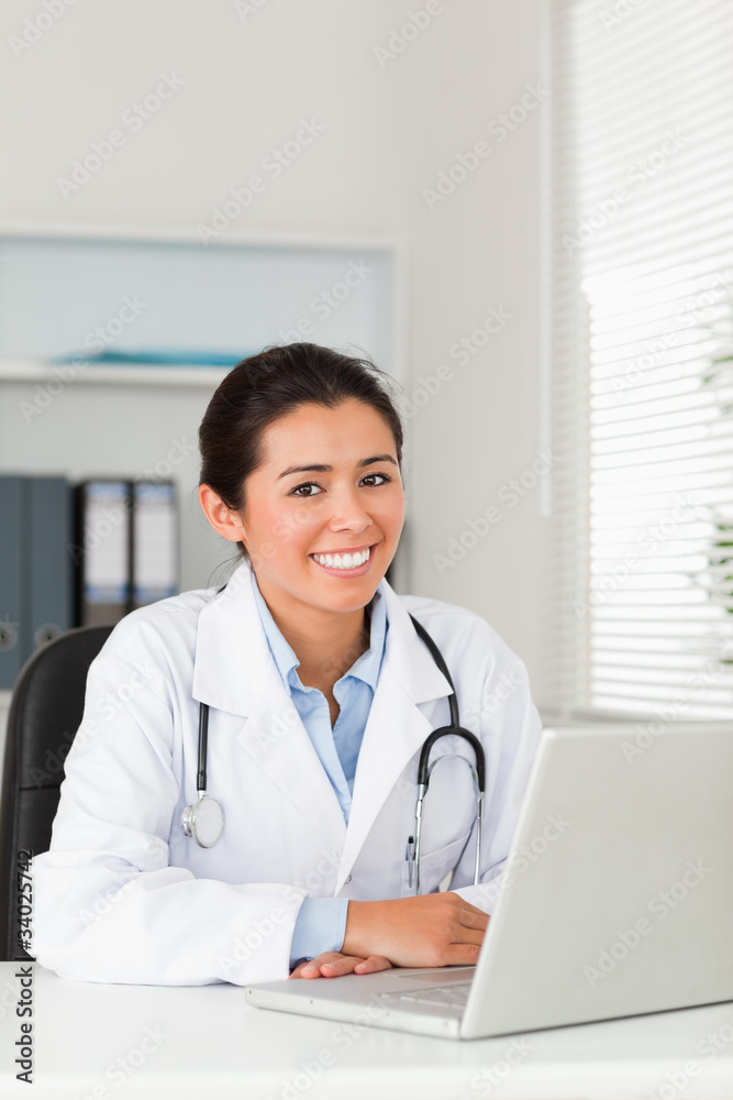 Lovely female doctor working with her laptop while posing Lovely female doctor working with her laptop while posing
