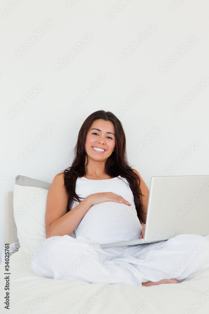 Good looking pregnant woman relaxing with her laptop while lying Good looking pregnant woman relaxing with her laptop while lying