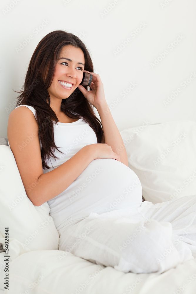Attractive pregnant woman on the phone while lying on a bed Attractive pregnant woman on the phone while lying on a bed