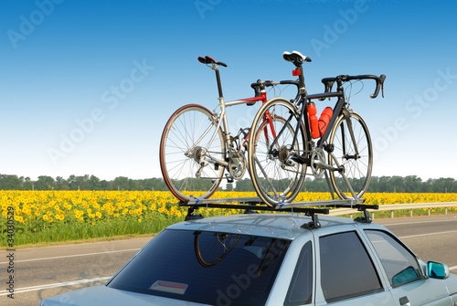 two bicycles mounted on roof of car against sky