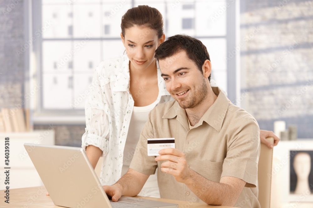 Happy couple shopping online at home smiling