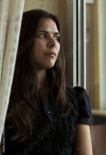 Young woman at home sitting near the window and looking