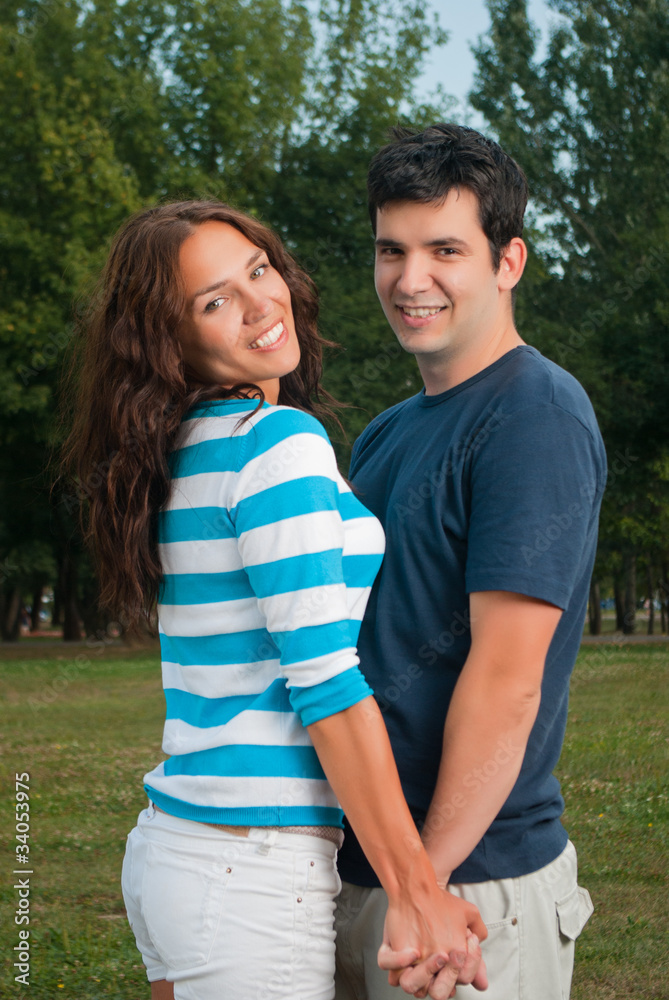 Young couple holding hands and smiling in park Young couple holding hands and smiling in park