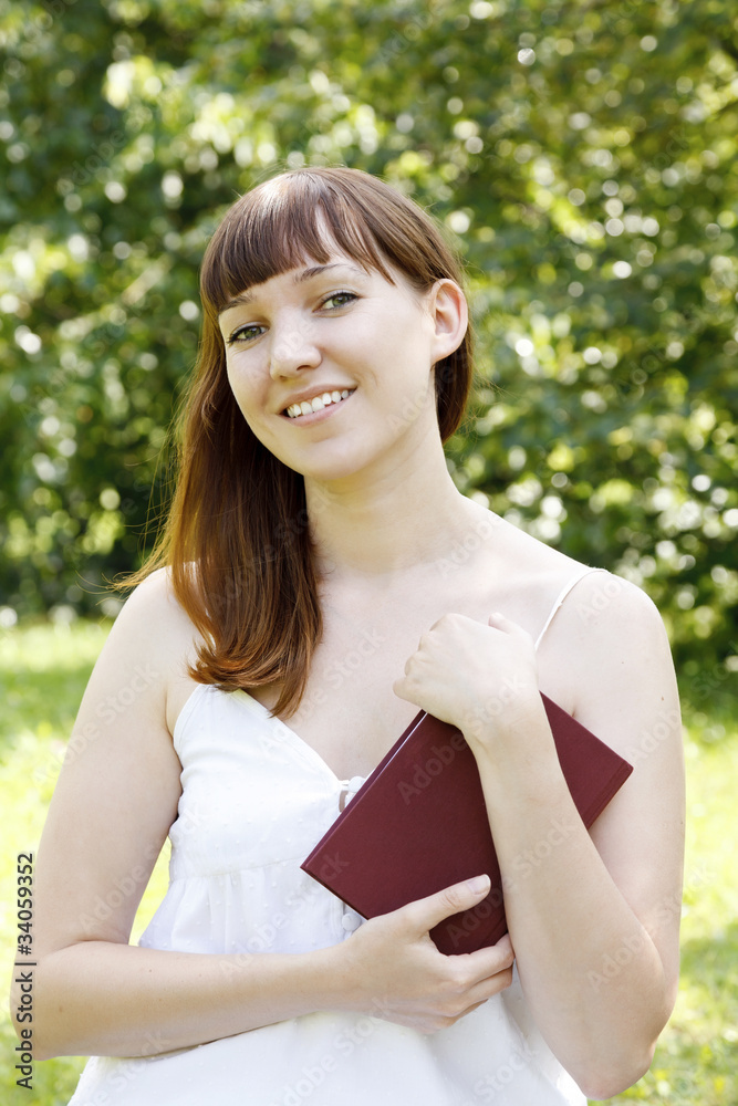 Portrait of a woman with a book outdoors