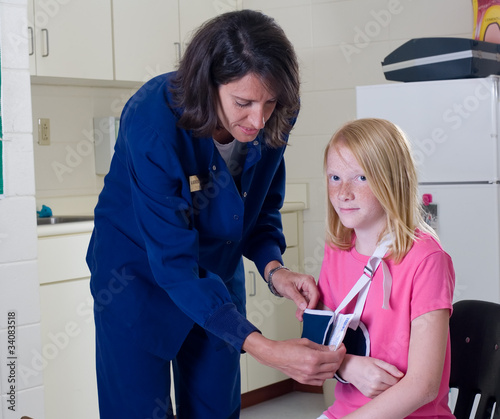 School nurse checking sling for broken arm