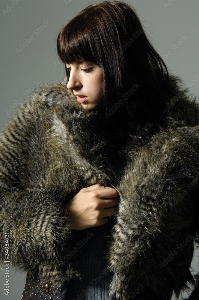 Attractive woman in fur coat on gray background Attractive woman in fur coat on gray background