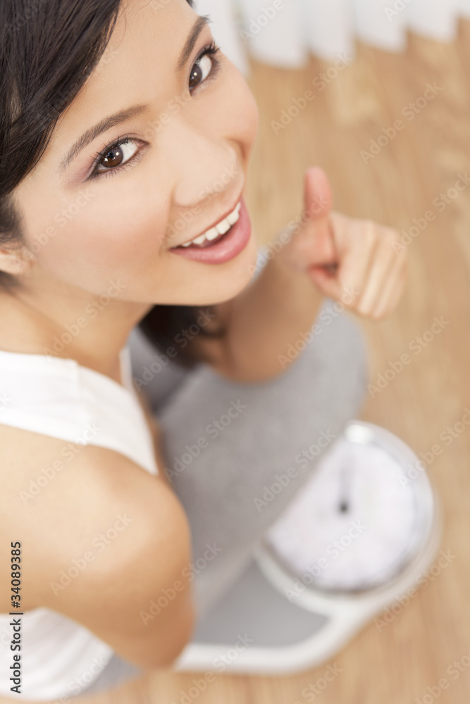 Asian Chinese Woman Thumbs Up Weighing Herself on Scales Asian Chinese Woman Thumbs Up Weighing Herself on Scales