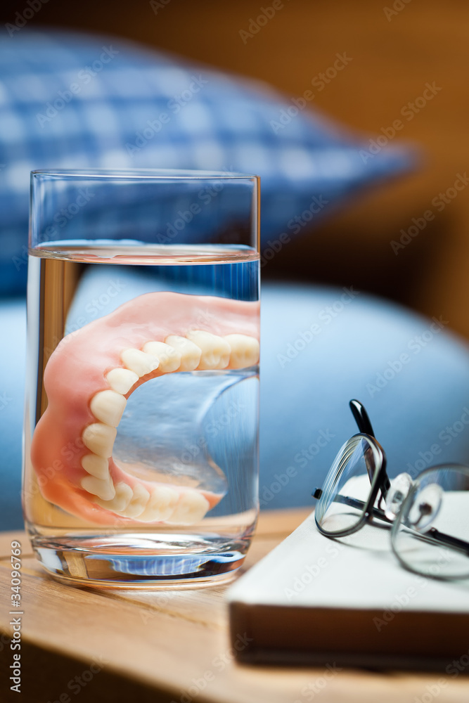 Denture in a glass of water on the bedside.