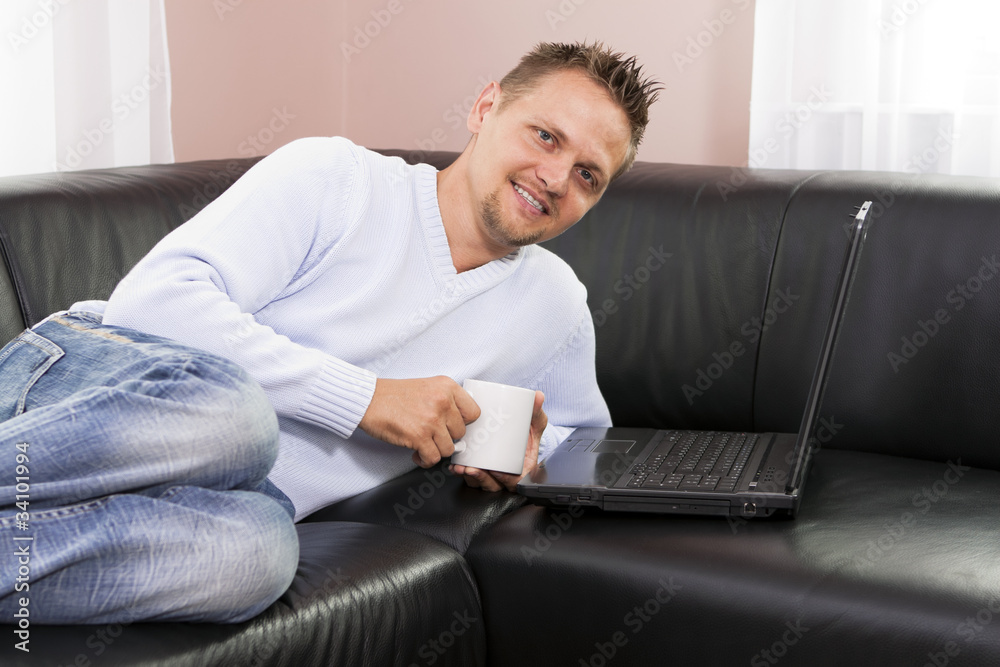 Man resting on sofa and using a computer. Man resting on sofa and using a computer.
