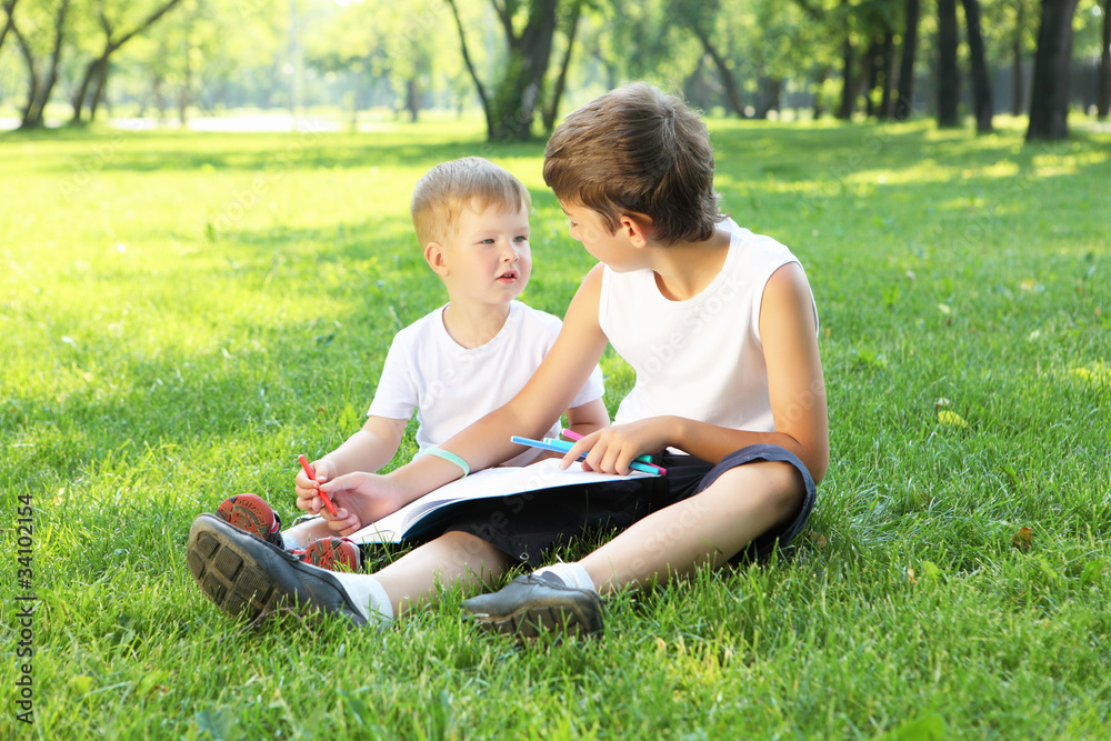 Children in the park reading a book