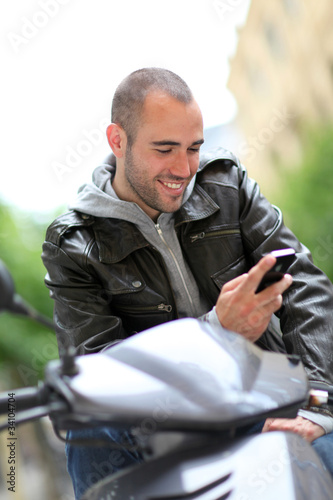 Young man sitting in motorcycle with telephone