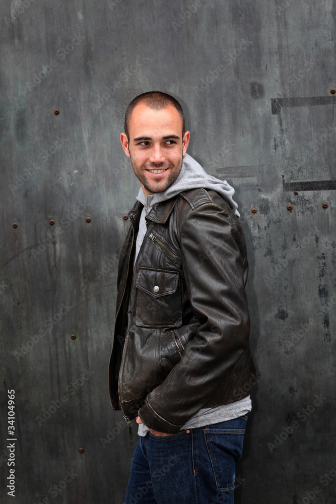 Man with leather jacket standing on metal door Man with leather jacket standing on metal door
