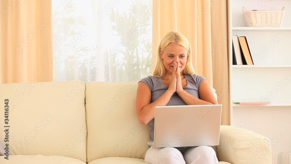 Woman with a notebook on her lap while sitting on a sofa Woman with a notebook on her lap while sitting on a sofa