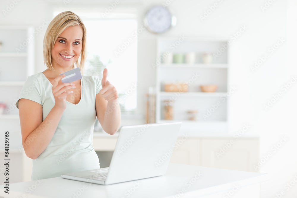 Blonde woman with credit card and notebook holding thumb up Blonde woman with credit card and notebook holding thumb up