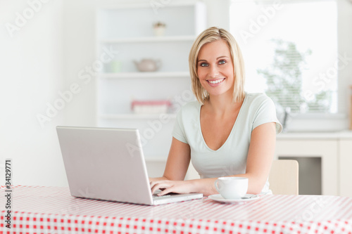 Woman sitting at a table with cup of coffee and notebook looking