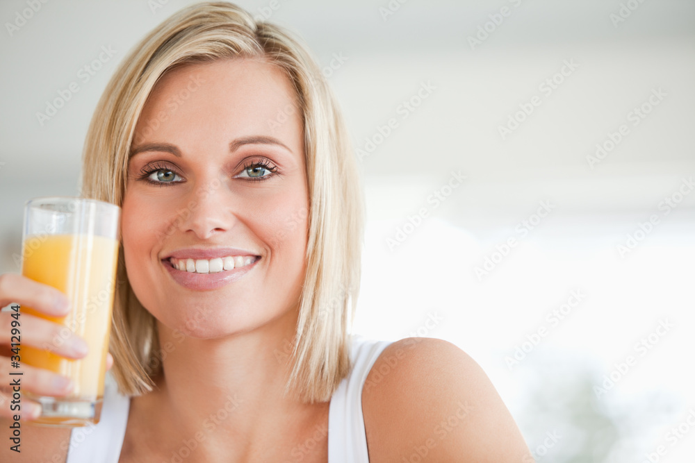 Close up of a smiling woman toasting with orange juice Close up of a smiling woman toasting with orange juice