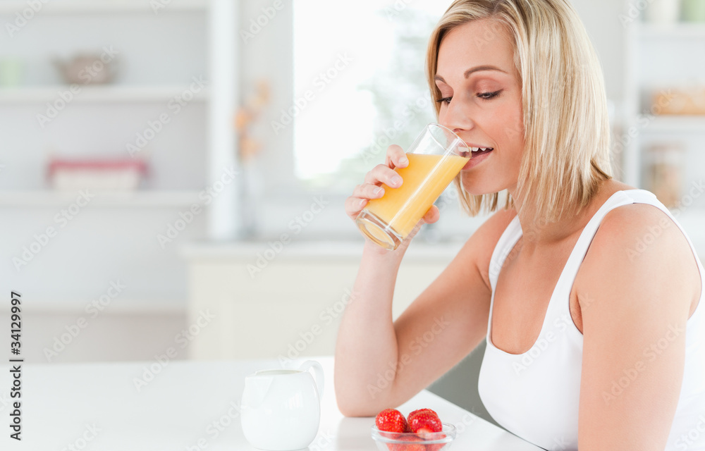 Woman sitting at a table drinking orange juice Woman sitting at a table drinking orange juice