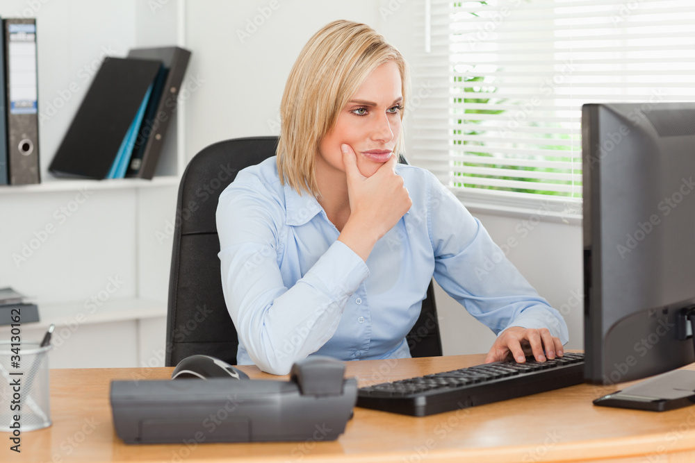 Working thoughtful woman in front of a screen looking at it