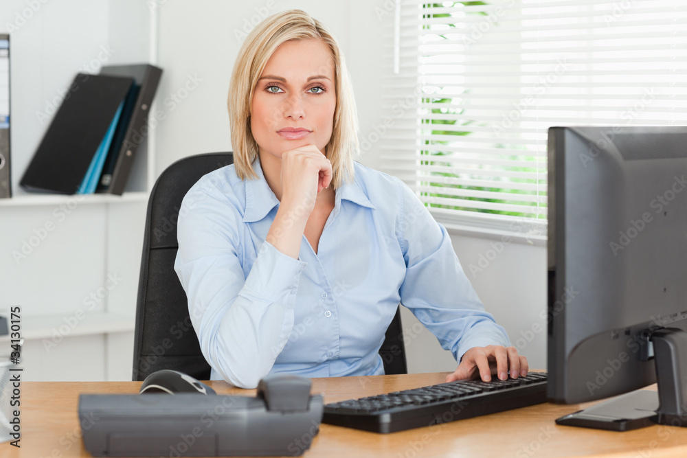 Working serious woman in front of a screen looking into camera Working serious woman in front of a screen looking into camera