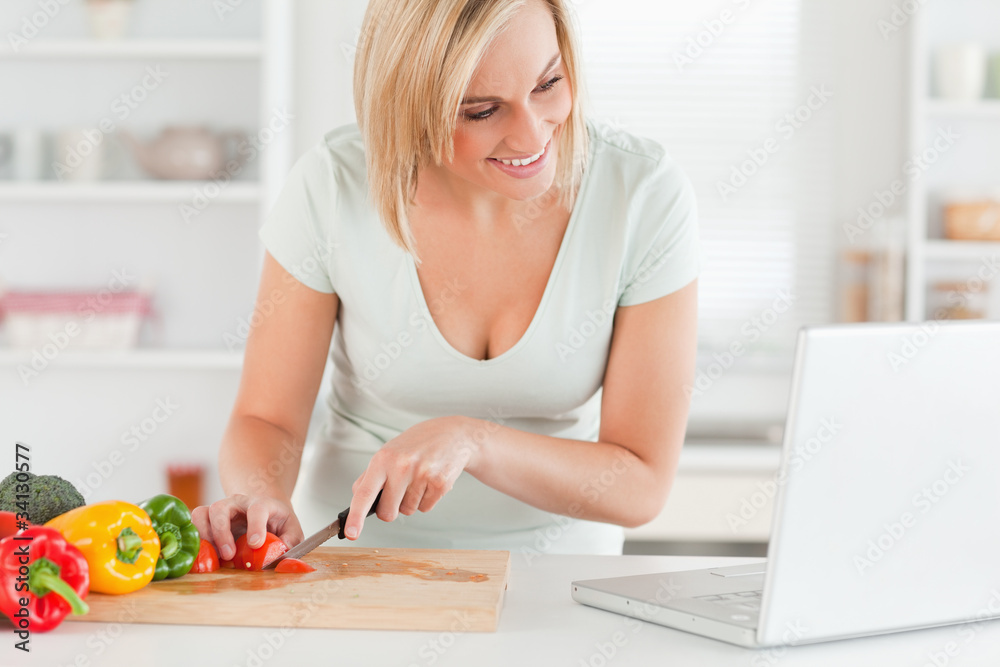 Woman enjoying cooking looking for a recipe on the laptop Woman enjoying cooking looking for a recipe on the laptop