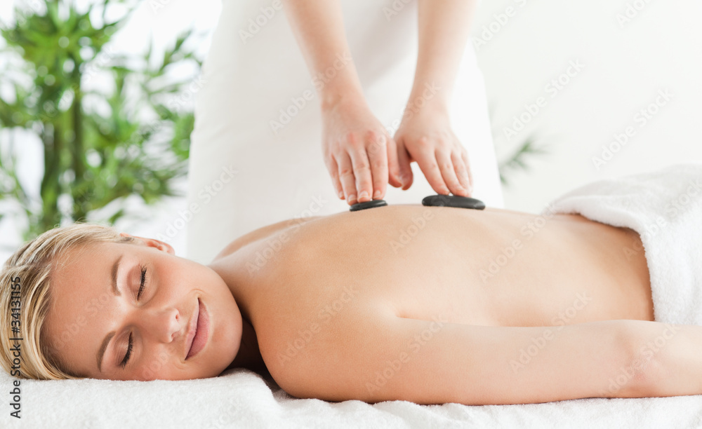 Blonde relaxed woman experiencing a stone therapy with eyes shut Blonde relaxed woman experiencing a stone therapy with eyes shut