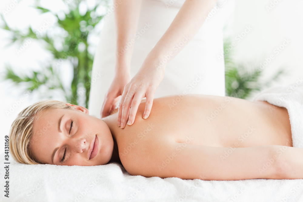 Gorgeous woman relaxing on a lounger during massage with eyes cl Gorgeous woman relaxing on a lounger during massage with eyes cl