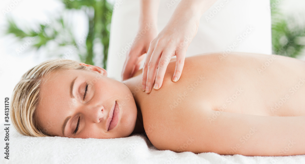 Cute woman relaxing on a lounger during massage with eyes closed Cute woman relaxing on a lounger during massage with eyes closed