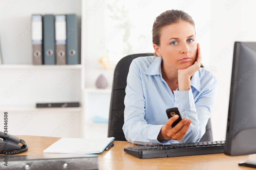 Thoughtful working woman using a mobile phone Thoughtful working woman using a mobile phone
